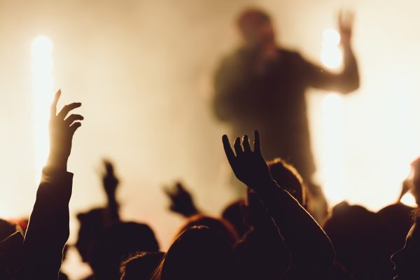 People dancing at a concert while the singer is performing surrounded with lights